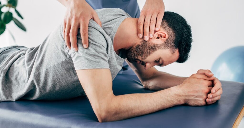 chiropractor massaging shoulder and neck of man on VDEHHPS 02